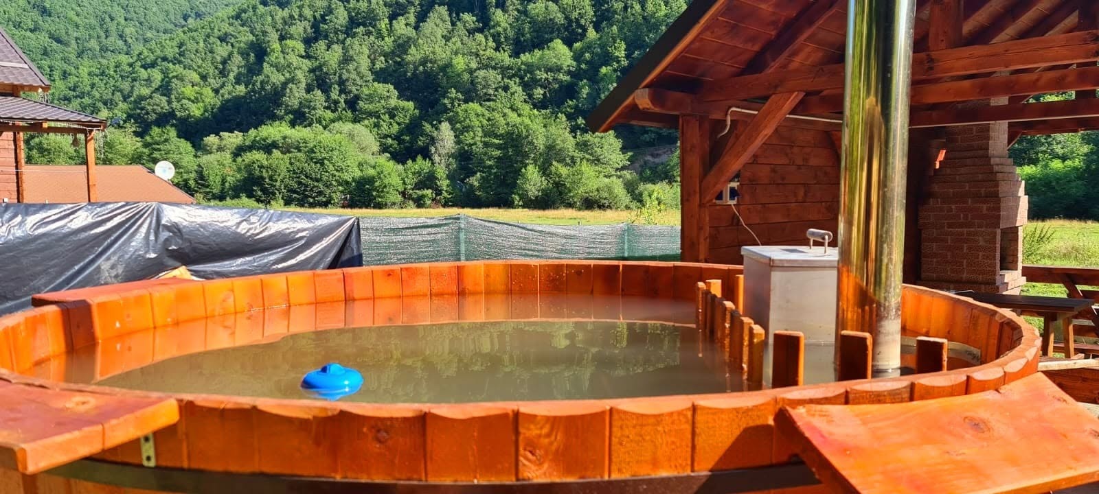 Piscina rotundă din lemn, cu munții în fundal