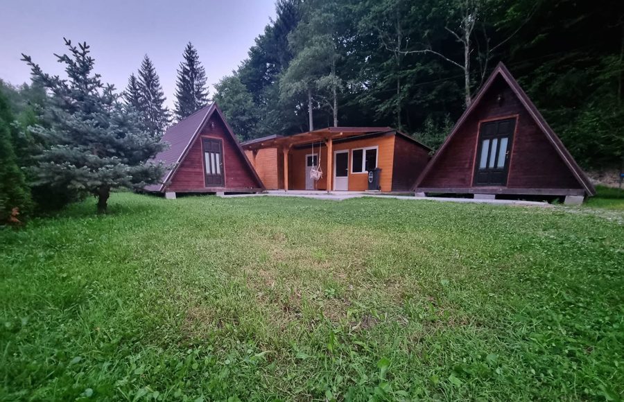 Cele două căsuțe A-frame și clădirea cu bucătăria, în curtea cu gazon